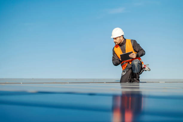 A worker using tablet to test solar panels on the rooftop. A handyman using tablet for solar panels testing on the roof. power equipment stock pictures, royalty-free photos & images