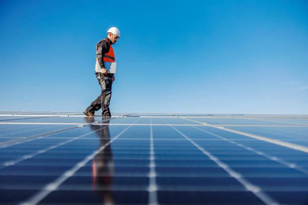 istock A worker walking around roof with solar panels with laptop under armpit. 1386418449