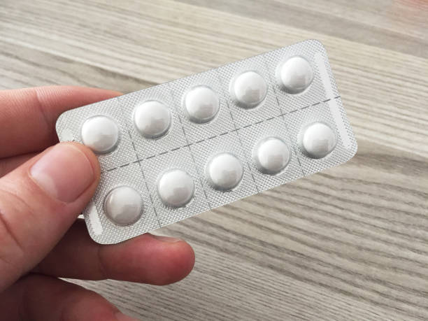 istock Hand holding pill blister pack with wooden table background 1386420610