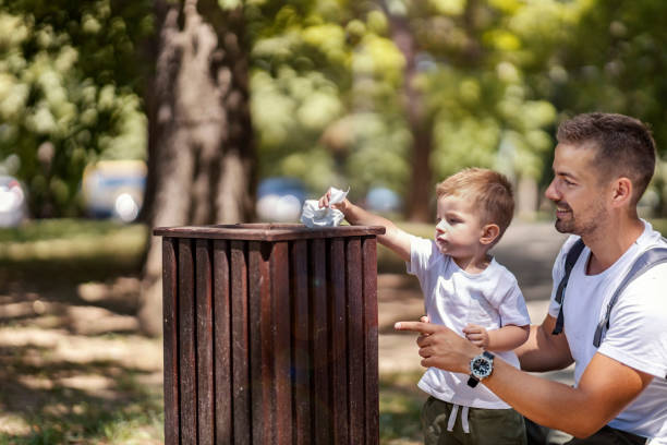 istock Father teaching his son to throw a trash into a bin. 1386421989