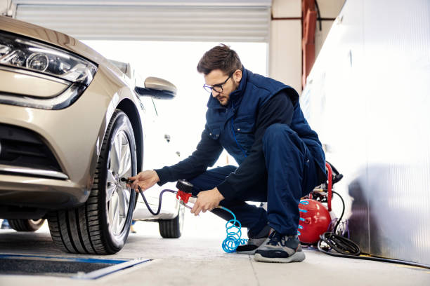 a focused auto mechanic inflates the tire at workshop. - inflating imagens e fotografias de stock