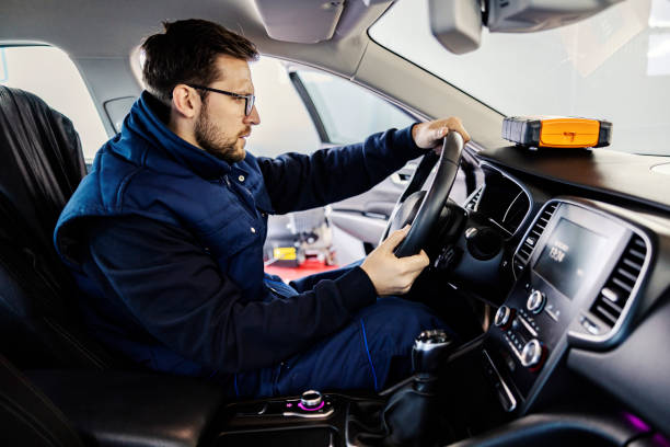 istock A mechanic sitting in a car and checking on steering wheel at workshop. 1386425271