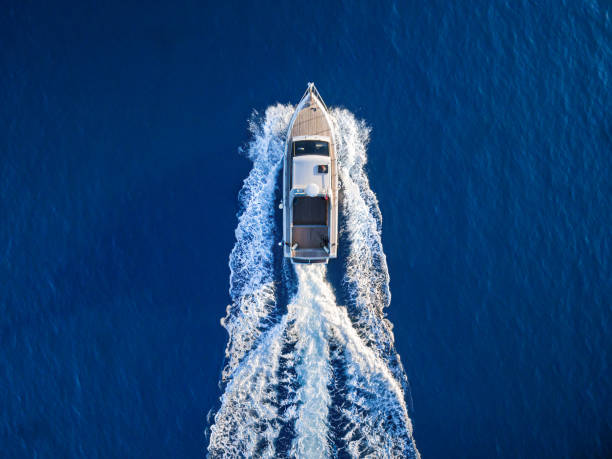 Speedboat racing along the open sea Fast speedboat racing along the open sea leaving white trail. High angle view from drone. nautical vessel stock pictures, royalty-free photos & images