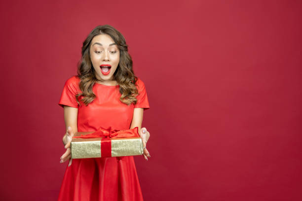 istock Enthusiastic woman with a gift on a red background 1386428338