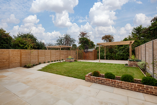 Cottenham, Cambridgeshire - Sept 7 2018: Rear landscaped gardens of brand new home incorporating raised beds, stone patio, pergola and decking area with high fencing