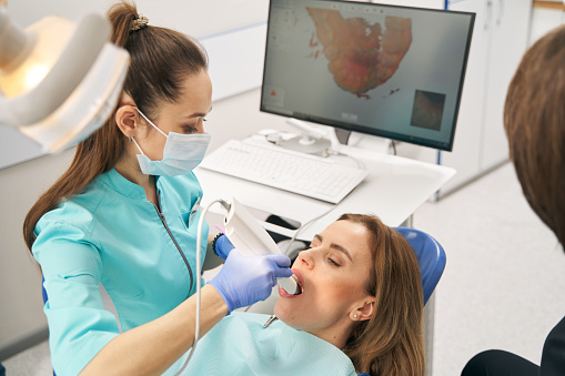 Dentista que escanea los dientes de la mujer con escáner 3D intraoral dental photo