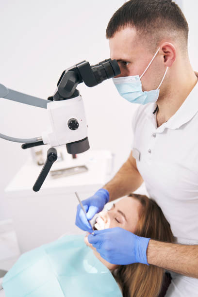 istock Dentist performing dental treatment with microscope in clinic 1386446022