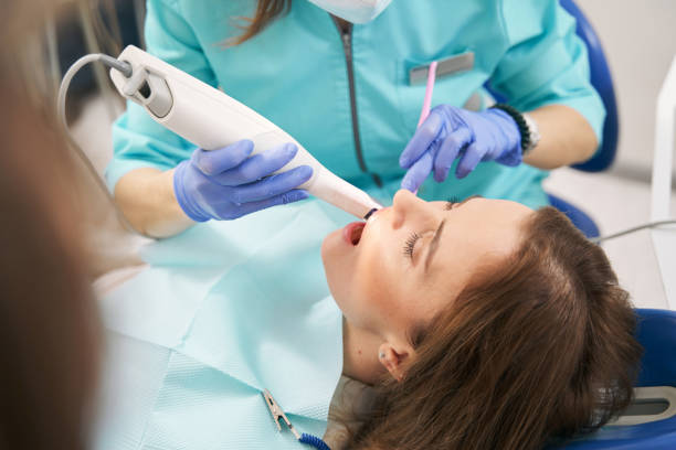 istock Dentist examining woman teeth with dental scanning device 1386446025
