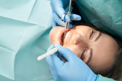 Close up of doctor hands in sterile gloves doing local anesthesia injection before dental procedure in stomatology clinic