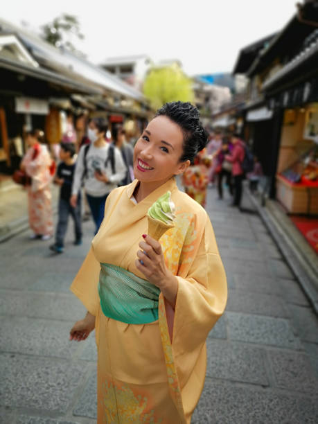 frau mit japanischer traditioneller kleidung mit einer tüte matcha-eis - kyoto protokoll stock-fotos und bilder