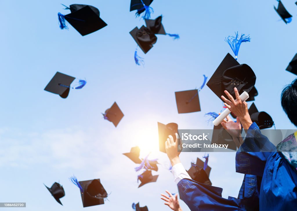 Graduating students hands throwing graduation caps in the air Graduating students hands throwing graduation caps in the air. Graduation Stock Photo
