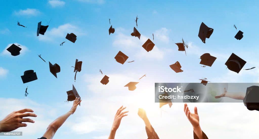 Graduating students hands throwing graduation caps in the air Graduating students hands throwing graduation caps in the air. Graduation Stock Photo
