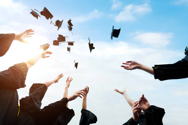 istock Graduating students hands throwing graduation caps in the air 1386452729