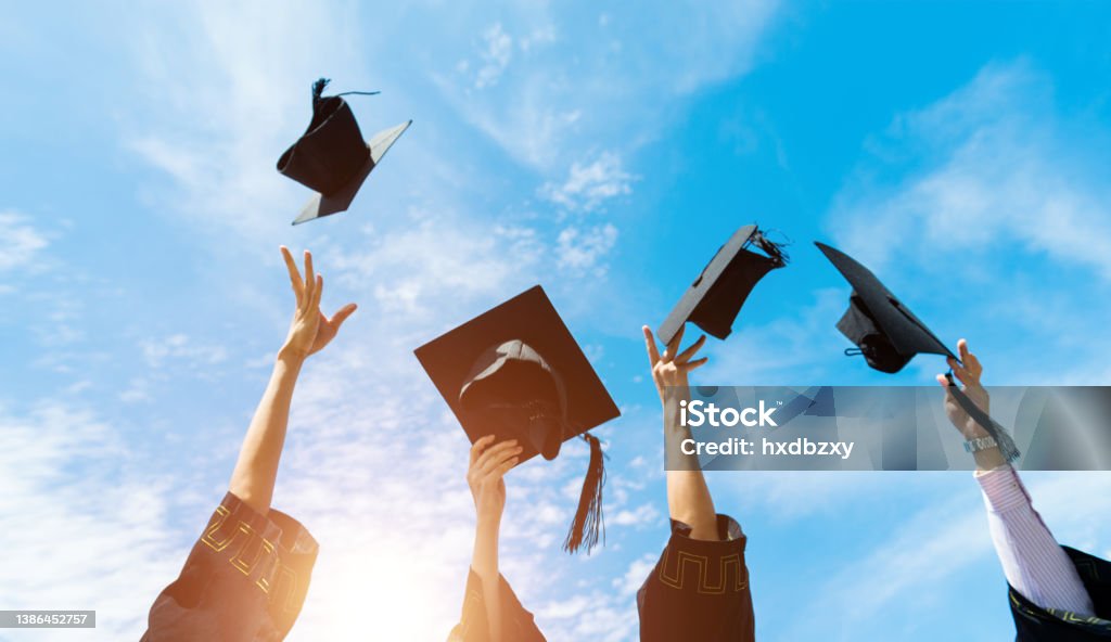 Four graduates throwing graduation hats in the air Four graduates throwing graduation hats in the air. Mortarboard Stock Photo