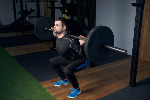 istock Man in sportswear doing exercise with barbell in gym 1386453807