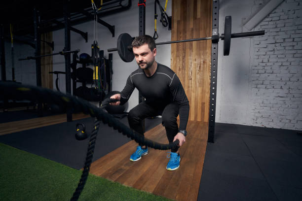 istock Man doing exercise with battle ropes in gym 1386453824