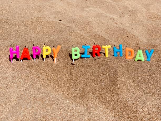 istock Happy birthday candles on sandy beach 1386459318