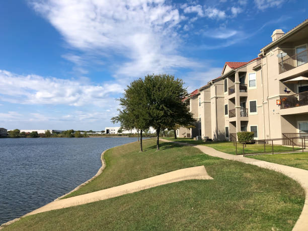 Rear view waterfront apartment complex with concrete pathway, grassy lawn in Lewisville, Texas, America