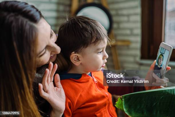 Mother Helping Her Son With His Hearing Aid Stock Photo - Download Image Now - Hearing Aid, Communication, Audiologist