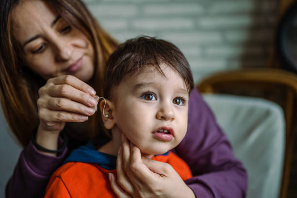 Mother helping her son with his Hearing Aid stock photo