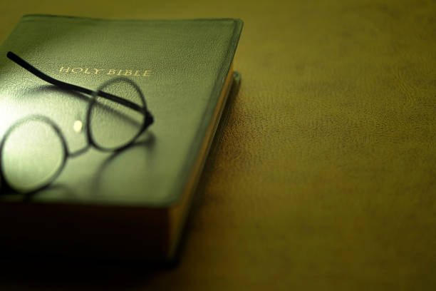 bibelbuch auf dem braunen lederhintergrund mit der brille - religiöse darstellung stock-fotos und bilder