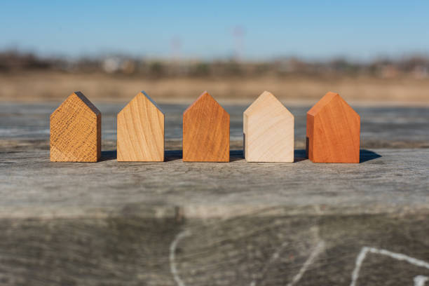 концепция недвижимости. крошечные отдельно стоящие деревянные модели домов в ряд. - modular стоковые фото и изображения