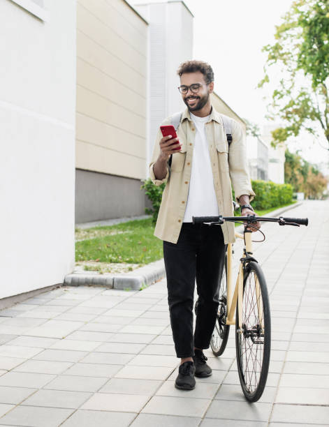 Happy man with bicycle using smart phone in a city