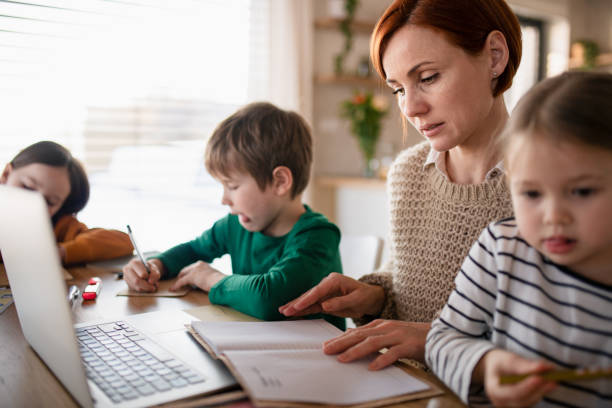 madre di bambini piccoli che lavorano sul laptop durante l'apprendimento a distanza e fanno opere d'arte a casa. - home schooling foto e immagini stock