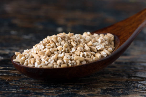 avena tagliata in acciaio su un cucchiaio di legno - steel cut oats foto e immagini stock