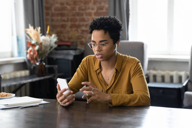 istock Serious focused Black millennial business woman in glasses using app 1386479270