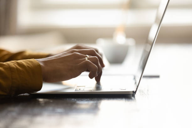 Hands of user typing on laptop keyboard at office table