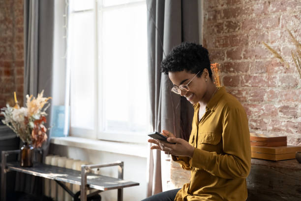 istock Happy Black girl using app on smartphone in modern home 1386479322