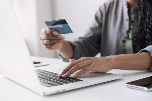 Young woman using laptop computer at home. Online shopping, spending money, business concept