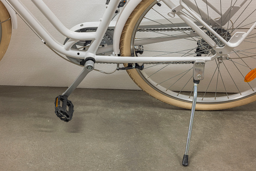 View of rear wheel of white bicycle with chain guard and parking leg. Sweden.