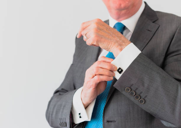 Portrait of a balding Caucasian man aged 60 wearing smart casual attire with a shirt and tie.