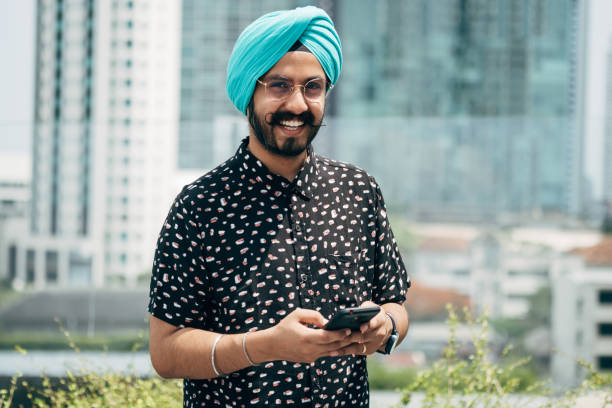 portrait d’un homme d’affaires indien heureux utilisant un téléphone portable à l’extérieur - technology typing male beauty asian and indian ethnicities photos et images de collection