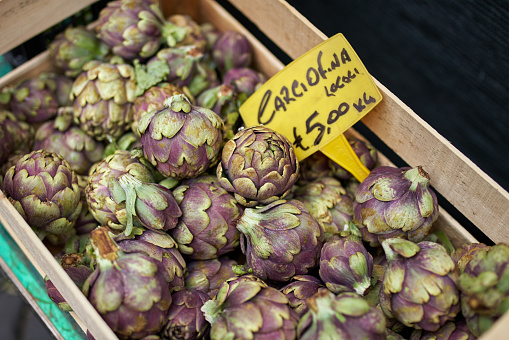 Pile of artichokes in a crate on display at a market.