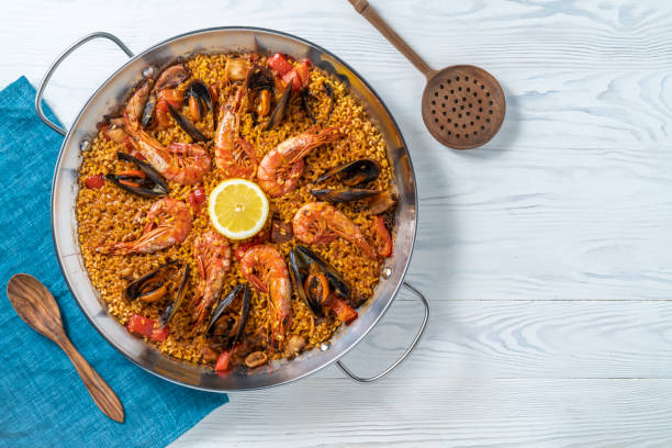 paella di mare ricetta dieta mediterranea con gamberi, calamari e cozze su legno bianco - mediterranean cuisine wood horizontal food and drink foto e immagini stock