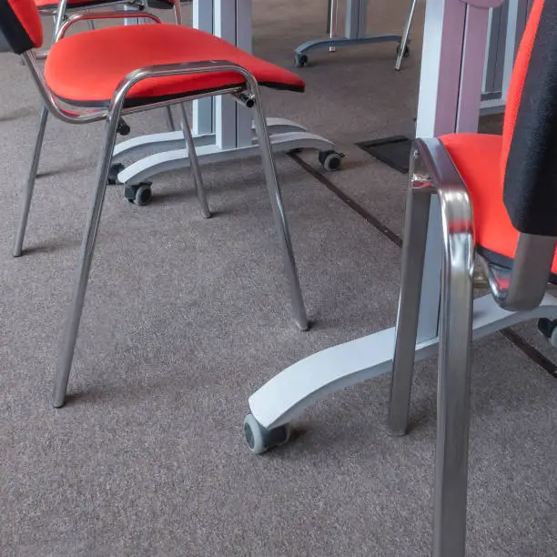 Desk legs with wheels and cropped empty red chairs in a meeting room