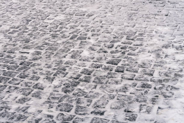 Cobblestone road covered wet snow. Winter season background image. Selective focus