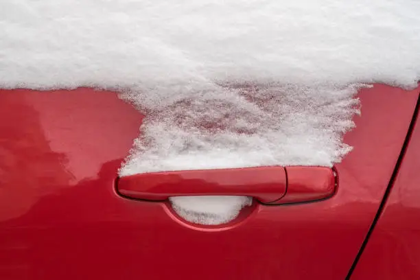 Red car handle in snowy winter season. Selective focus