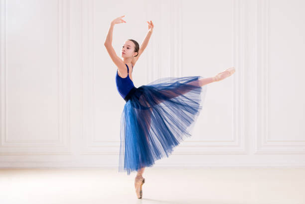 professional student ballerina doing pointe shoes in beautiful white room