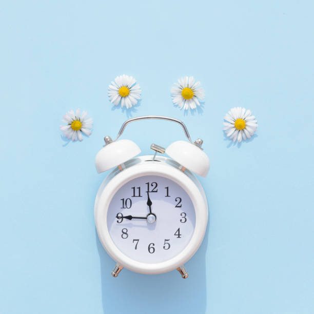 istock Old retro clock on a blue background with spring flowers. 1386502119