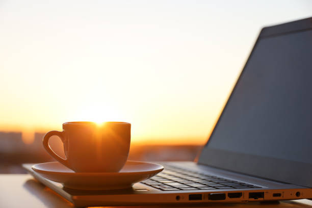 istock Coffee or tea cup on laptop against the window with sunshine 1386509511