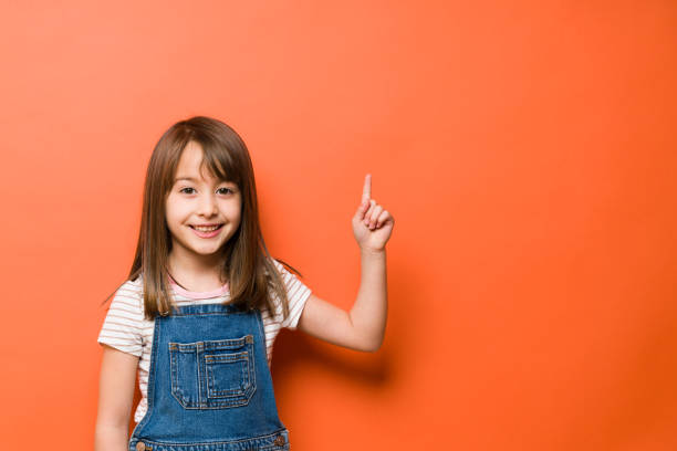 istock Beautiful girl pointing up to copy space 1386514697