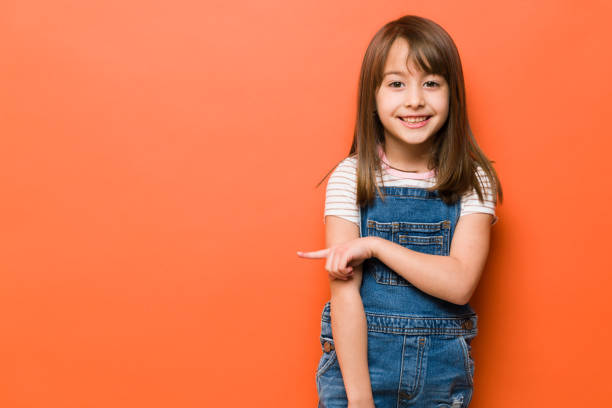 istock Cute girl pointing towards copy space 1386514700