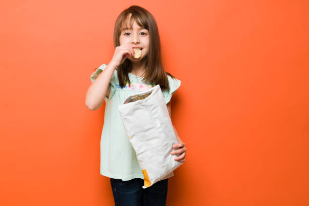 Little girl eating junk food in a studio stock photo