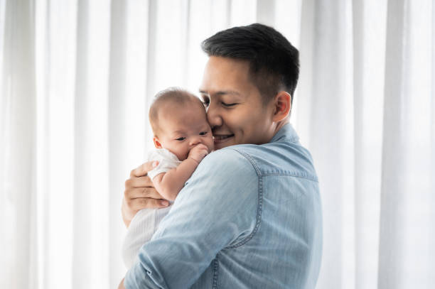 father holding baby daughter and kissing Asian father holding baby daughter and kissing with love at home father and baby stock pictures, royalty-free photos & images
