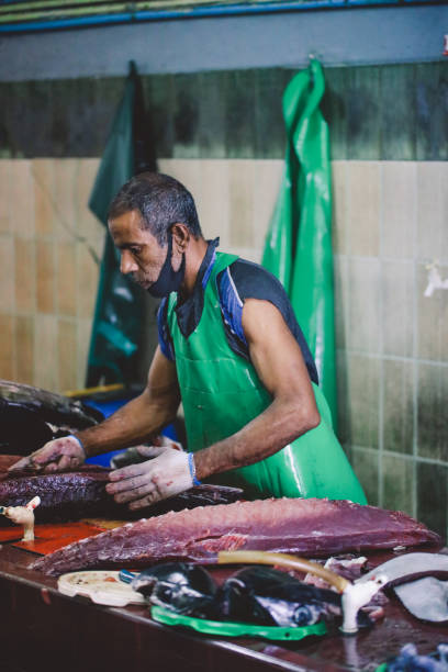 Local Maldivian Fisherman butcher a Big Tuna Fish on the Central Market of Male City Male, Maldives - June 25, 2021: Local Maldivian Fisherman butcher a Big Tuna Fish on the Central Market of Male City maldives fish market photos stock pictures, royalty-free photos & images