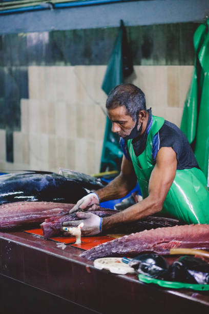 Local Maldivian Fisherman butcher a Big Tuna Fish on the Central Market of Male City Male, Maldives - June 25, 2021: Local Maldivian Fisherman butcher a Big Tuna Fish on the Central Market of Male City maldives fish market photos stock pictures, royalty-free photos & images